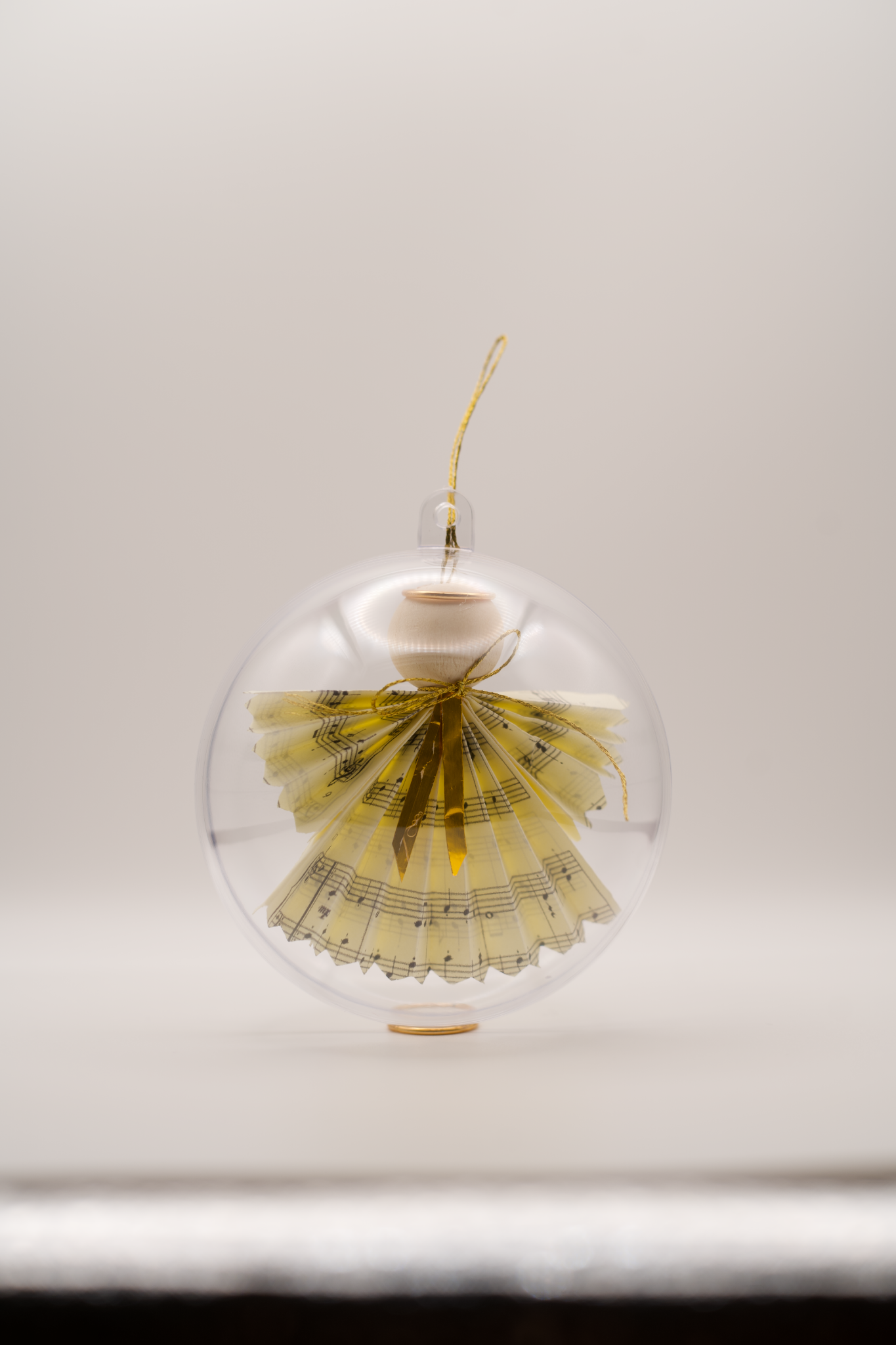 Angel ornament made from folded sheet music inside a clear round bauble